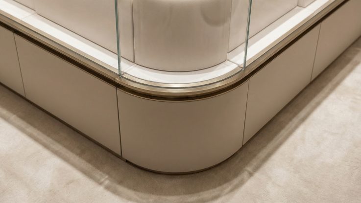 Özel üretim kavisli camın (curved glass) pirinç süpürgelik profili ve deri kaplama mobilya gövdesi ile birleşim noktası.