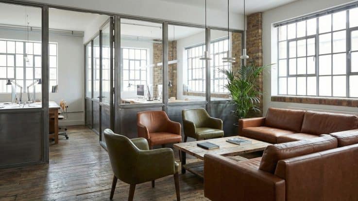 Endüstriyel loft tarzı ofiste kullanılan taba rengi deri chesterfield koltuklar ve tuğla duvar kaplaması.