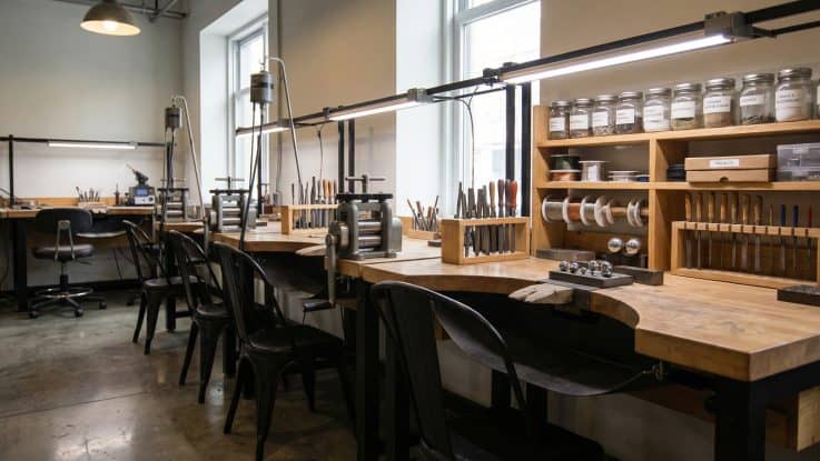 Metal ayaklı masif üretim tezgahları, kuyumcu silindir makinesi ve sadekarlık el aletleri düzeni.