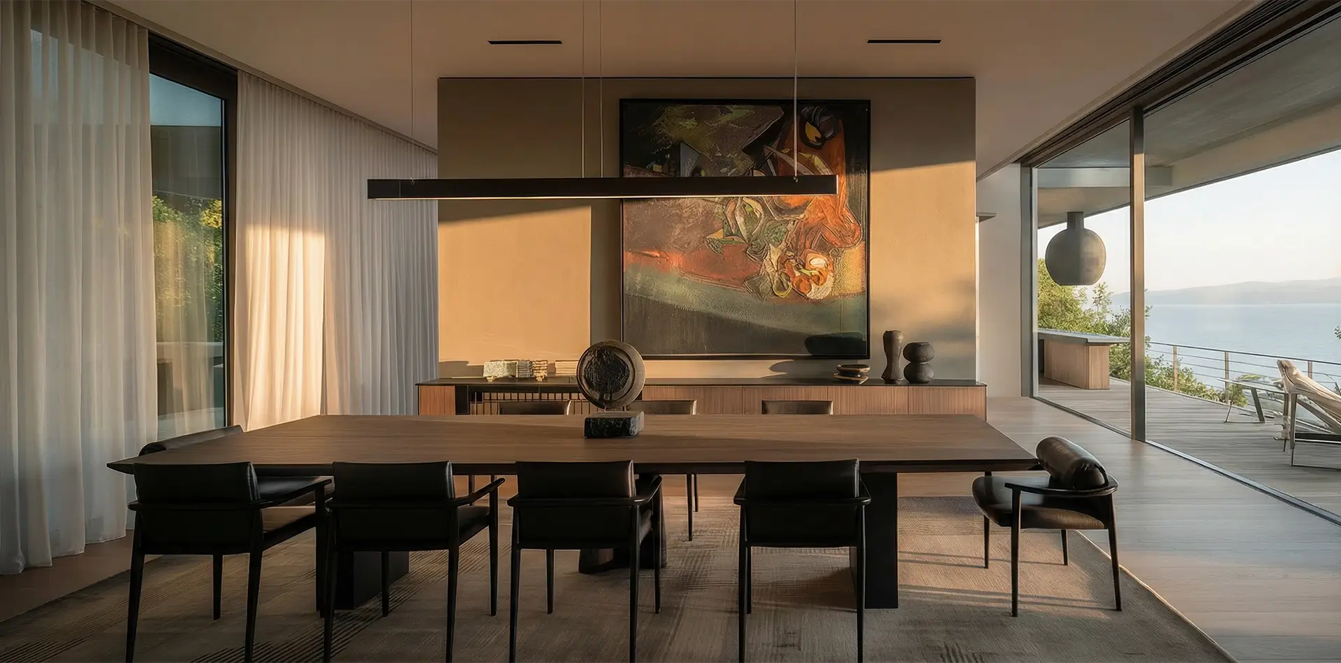 Modern villa tasarımı estetiğini vurgulayan masif ahşap yemek masası, brütalist dokulu duvar panelleri ve iç dış mekan sürekliliği sağlayan sürgülü cam doğramalar
